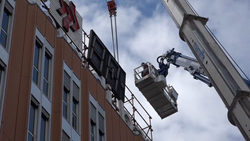 Dopo oltre mezzo secolo, l’orologio della Banca Popolare di Bari viene rimosso per lasciare spazio a una nuova insegna della Banca del Mezzogiorno.